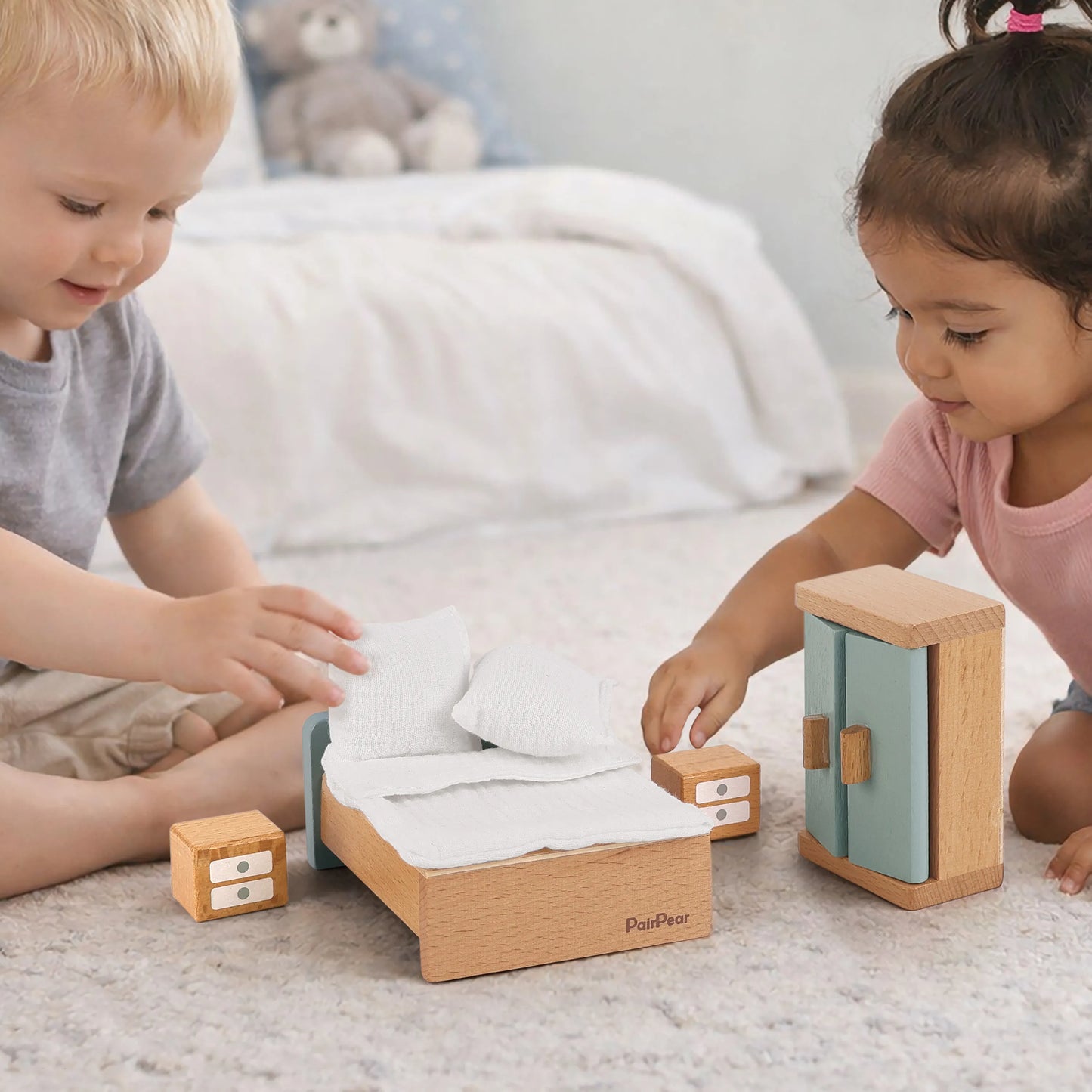 Kids enjoying pretend play with wooden dollhouse furniture. Toddlers arranging a miniature wooden bed, soft bedding, and a tiny wardrobe on a rug.
