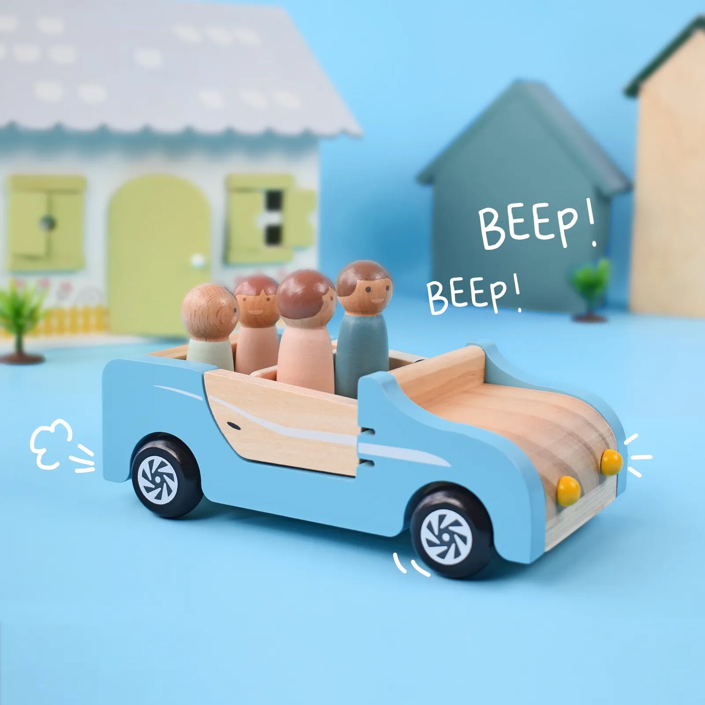 Four peg dolls riding in a blue wooden dollhouse family car. This cute pretend play toy car is parked outside a miniature house, ready for a road trip.