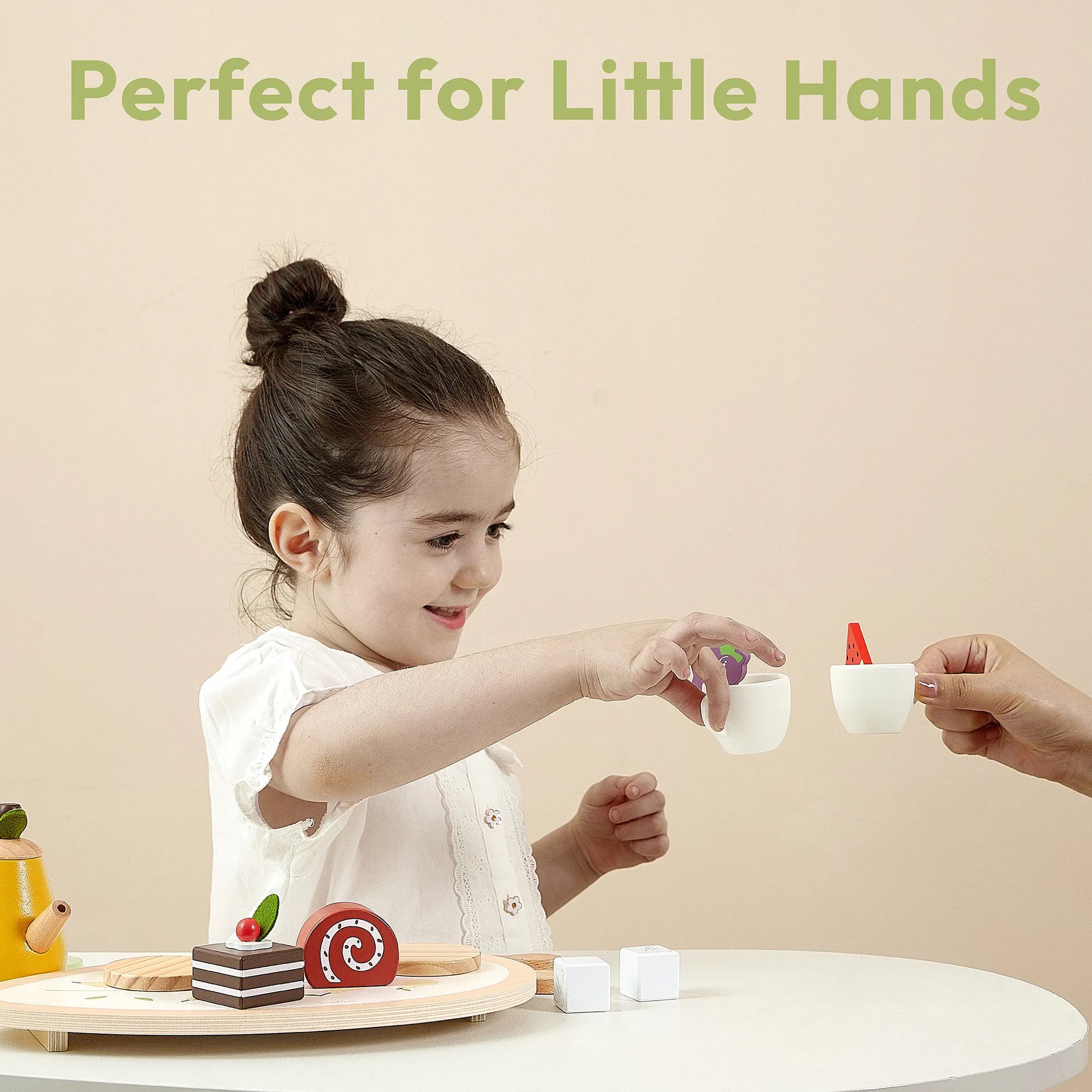 Toddler holding a wooden teacup during an imaginary tea party. This kids play food set is the perfect size for little hands to build motor skills
